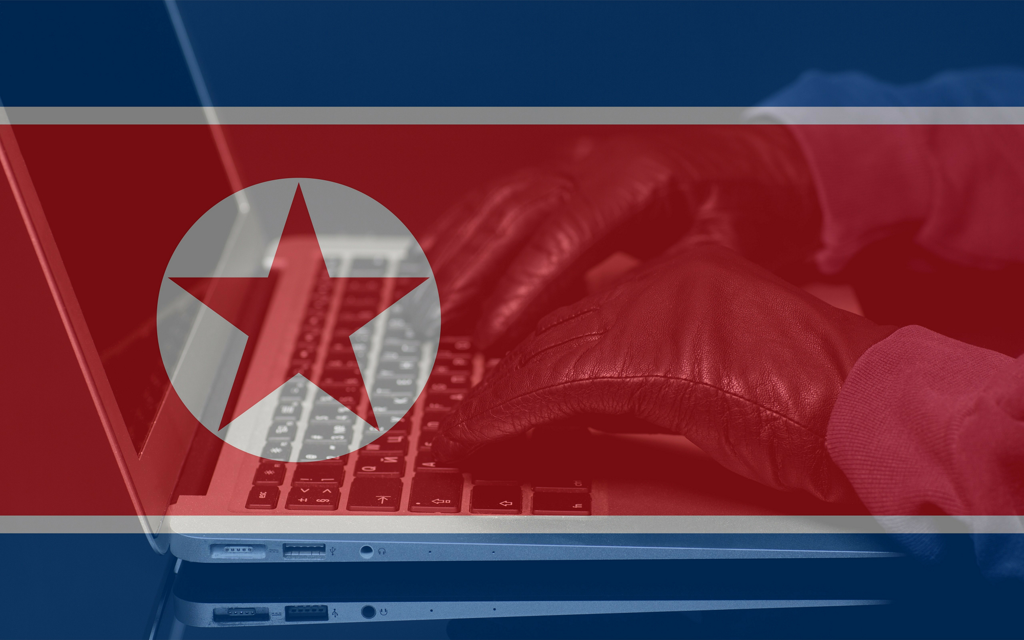 An image showing a hooded hacker using a computer against a backdrop of a North Korean flag.