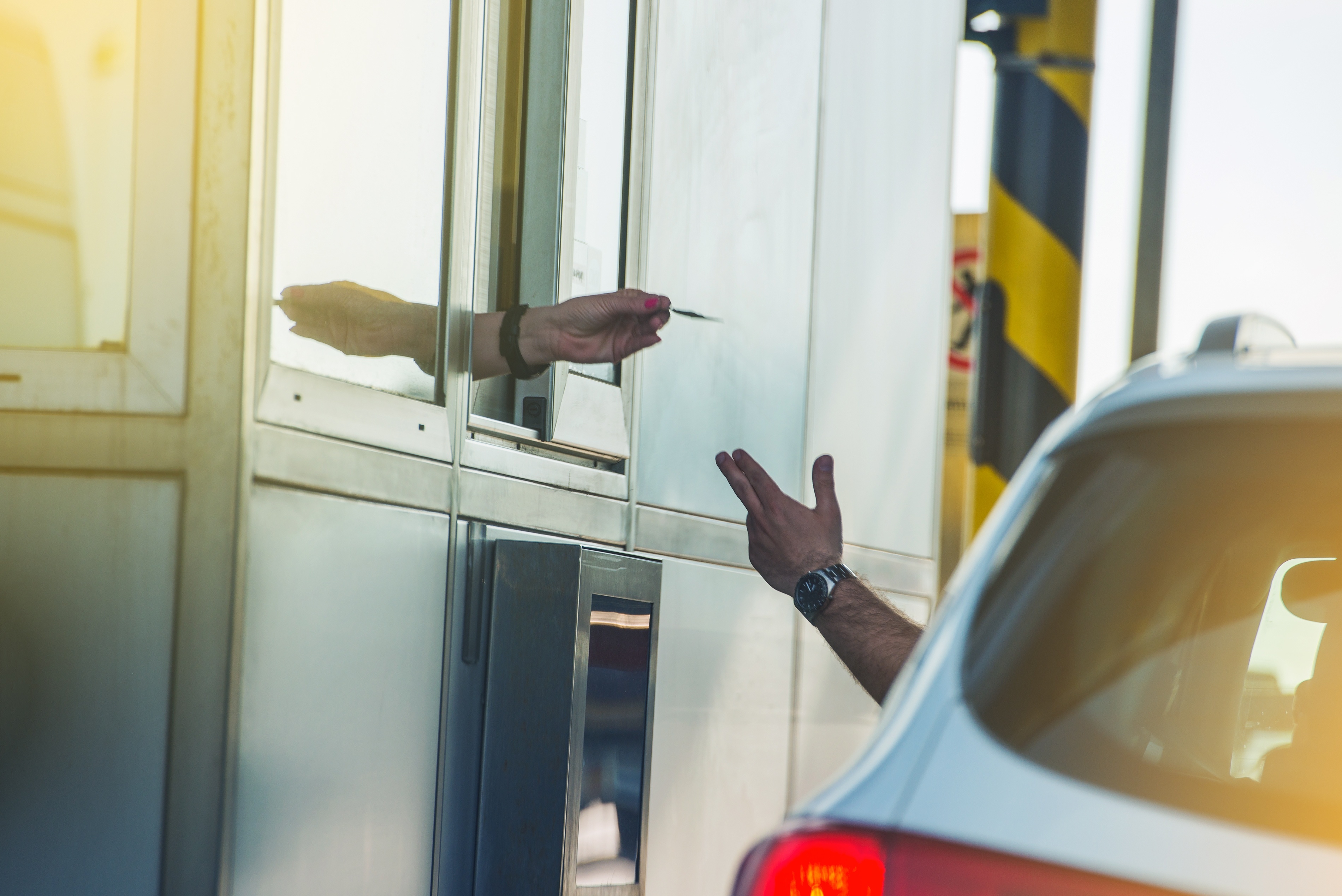 A car driver pays toll fees at a highway booth.
