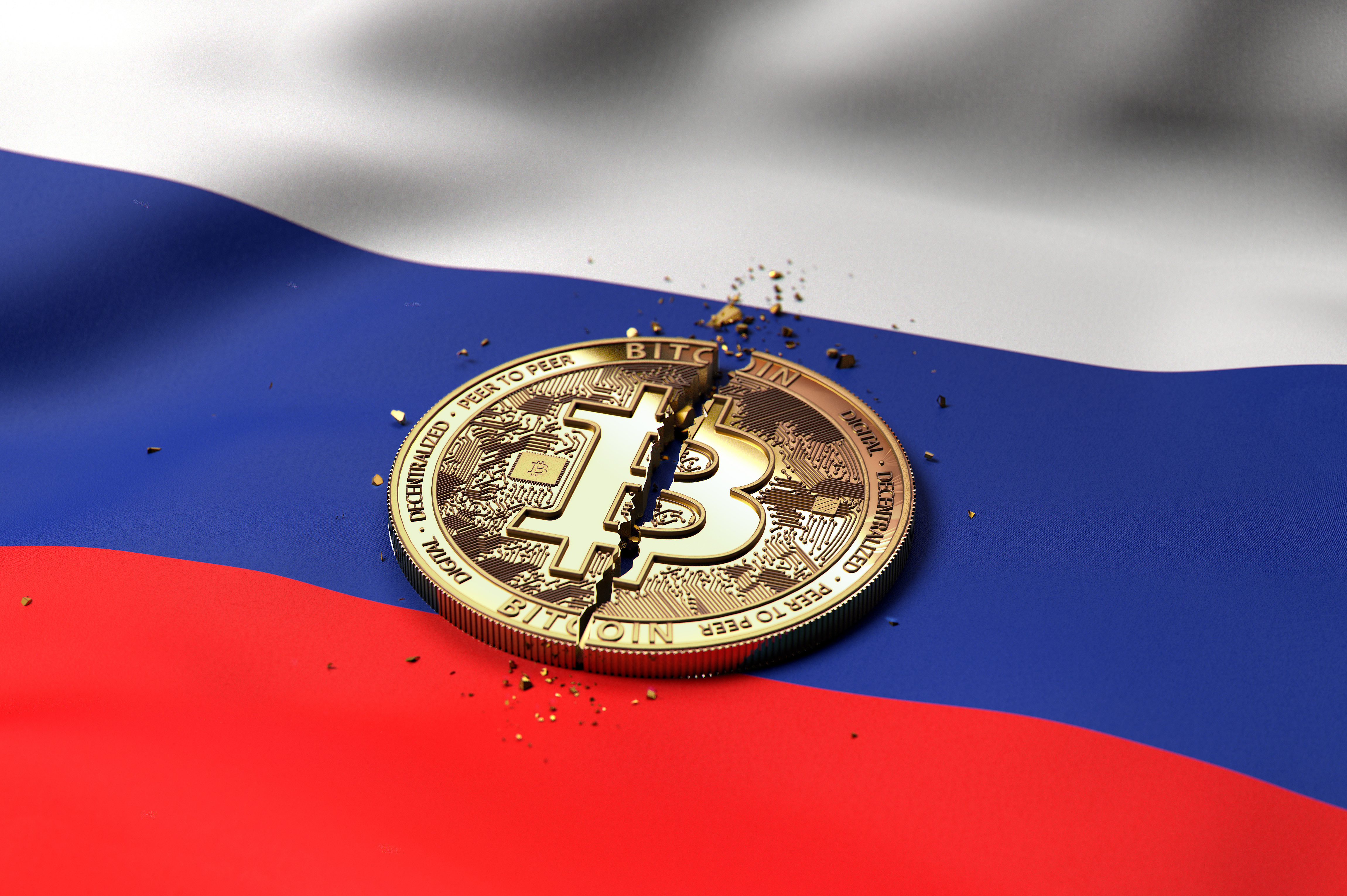 A torn token representing bitcoin rests on the Russian flag.