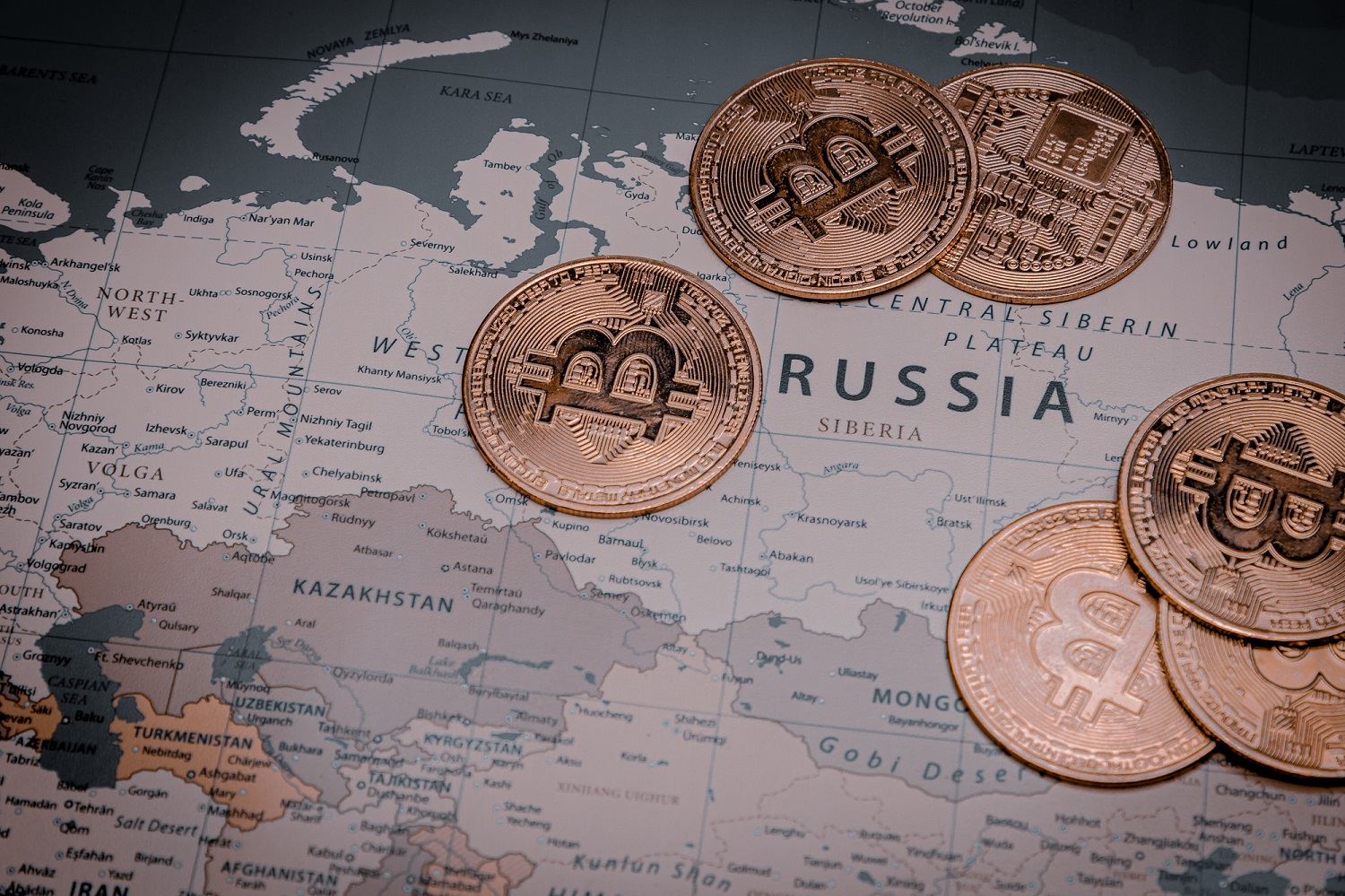 Bir dünya haritası üzerinde Rusya'yı temsil eden bir alanda Bitcoin'i temsil eden jetonlar.