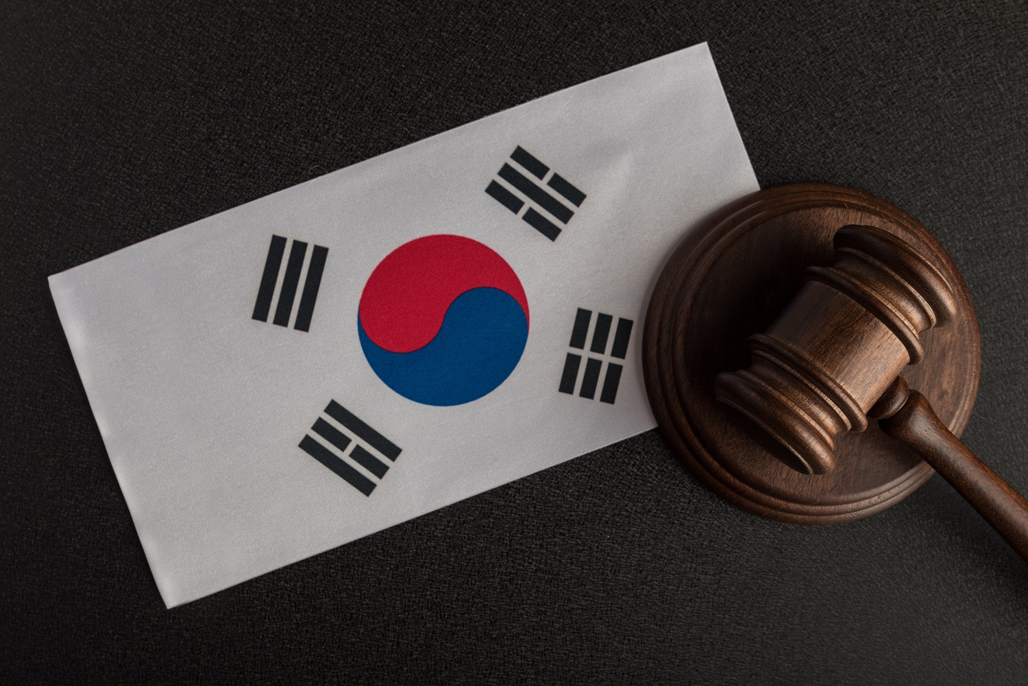 A gavel and block next to a South Korean flag on a wooden table.