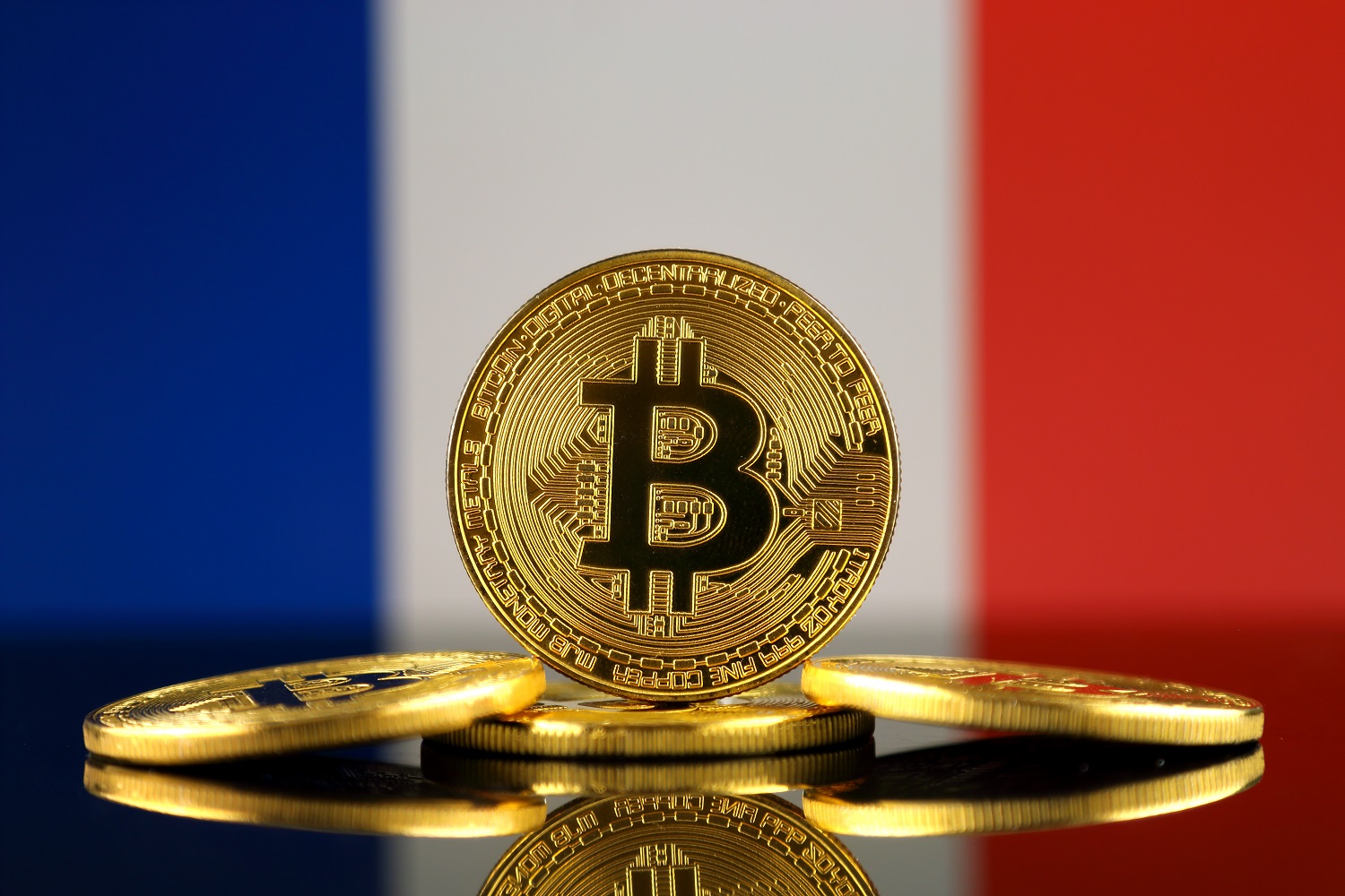 Bir Fransız bayrağının arka planında Bitcoin'i temsil eden madeni paralar.