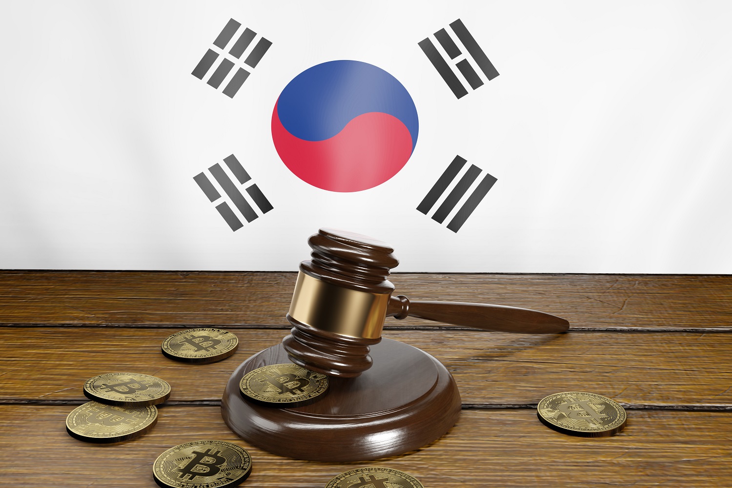 A gavel and block on a wooden table next to tokens intended to represent Bitcoin on the flag of South Korea.