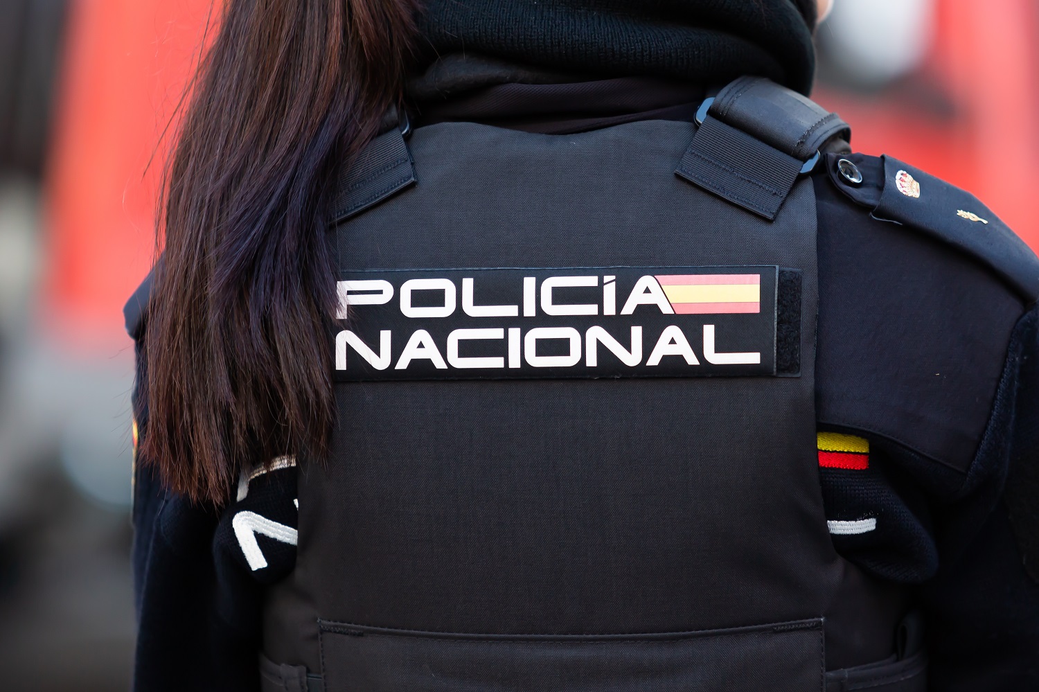 A Spanish police officer wearing a flack jacket, with the emblem of the National Police emblazoned on the rear.