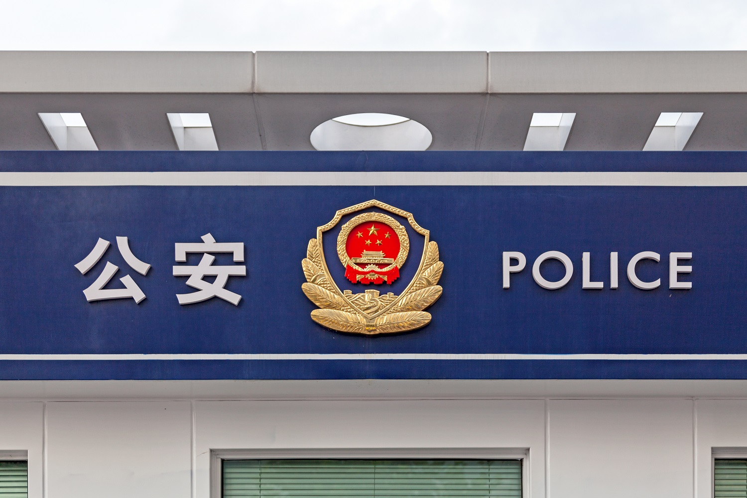 A sign that reads “police” in Chinese and English outside a Chinese police station.